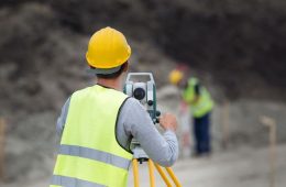 Surveyor engineers working with theodolite on road construction site